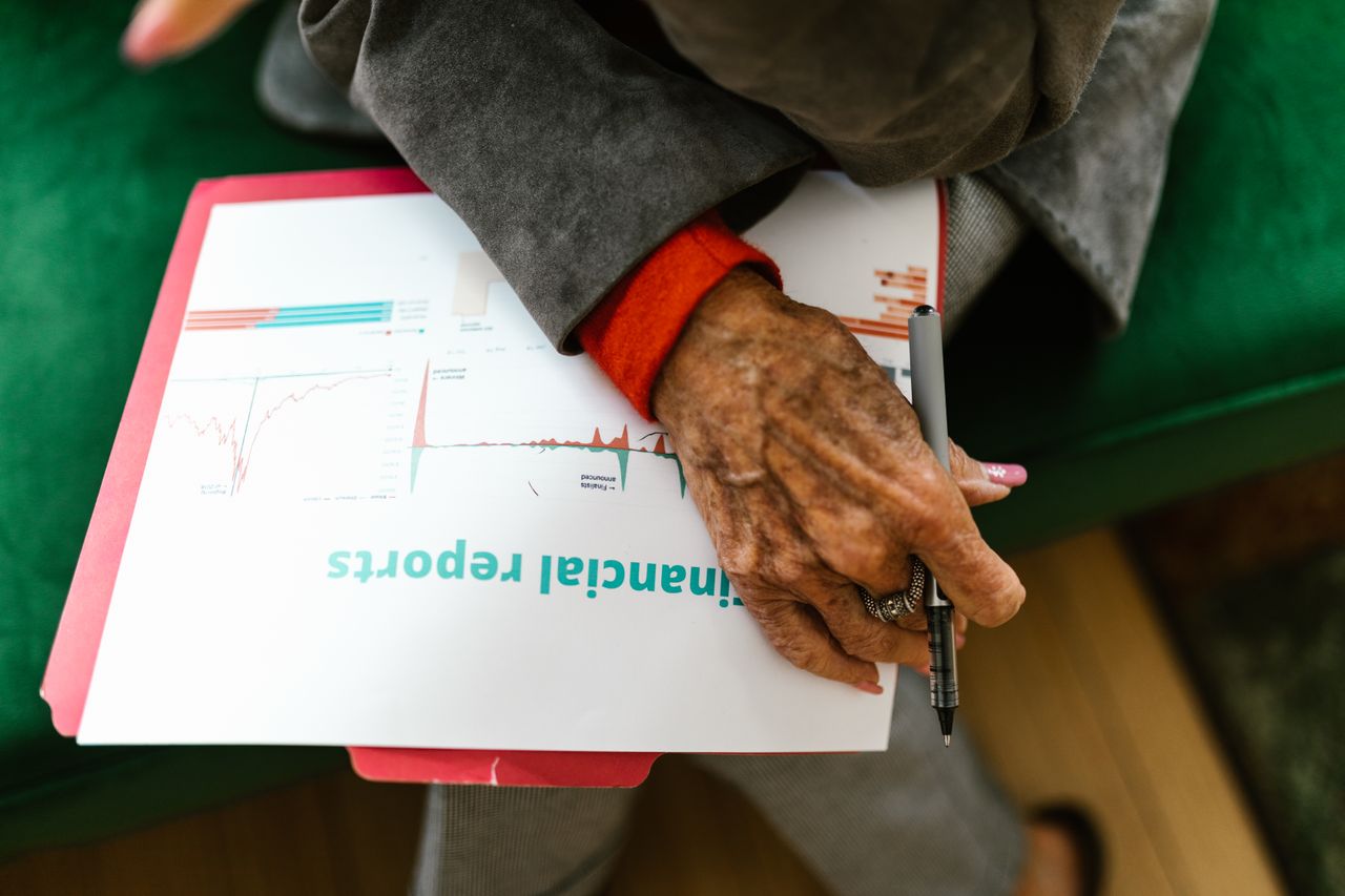 Elderly woman holding financial reports for gold in a retirement portfolio