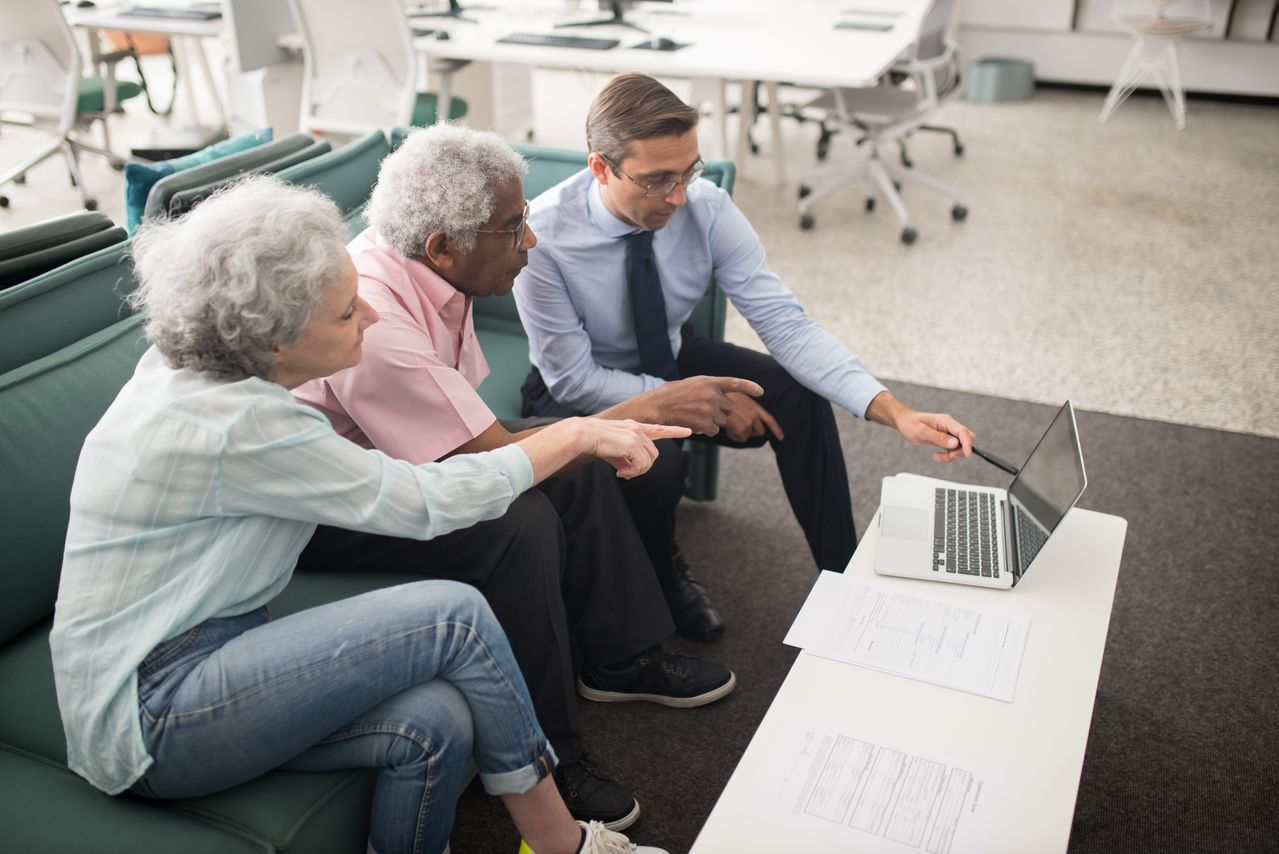 Elderly couple discussing risks and downsides of gold IRA rollovers with a precious metals specialist